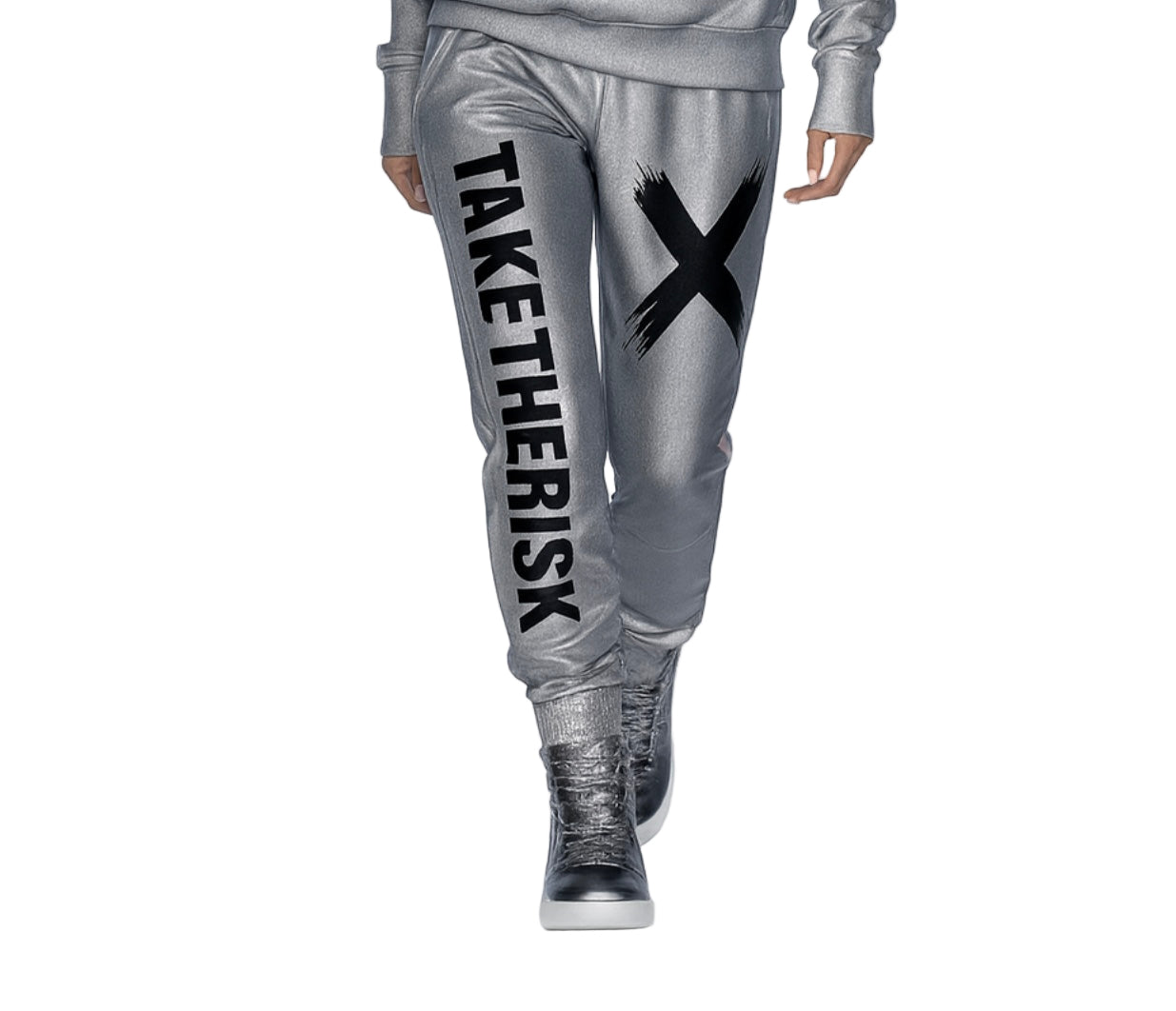 Person wearing silver jogger pants with 'TAKE THE RISK' text and black X, standing on a white background.