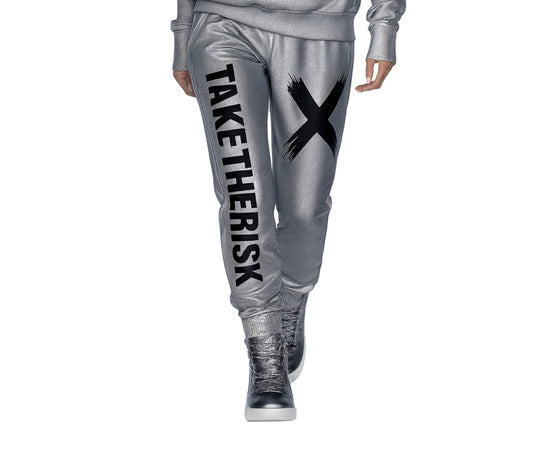 Person wearing silver jogger pants with 'TAKE THE RISK' text and black X, standing on a white background.